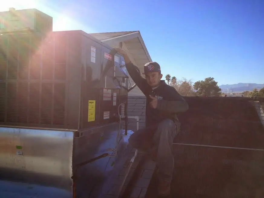HVAC technician performing AC Tune-Up on a rooftop unit in Riverside